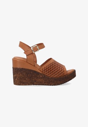 Brown wedge sandals with a textured cork sole, perforated upper design, and adjustable ankle strap featuring a metal buckle.