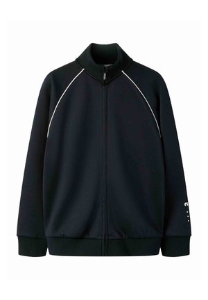 Chaqueta negra con cremallera y ribete blanco a lo largo de las mangas raglán, cuello, puños y dobladillo acanalados, y un pequeño logo blanco en el puño de la manga izquierda.