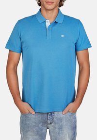 Polo shirt in cotone blu con maniche corte, una chiusura a due bottoni e un colletto azzurro a contrasto. Presenta un piccolo logo sul petto.