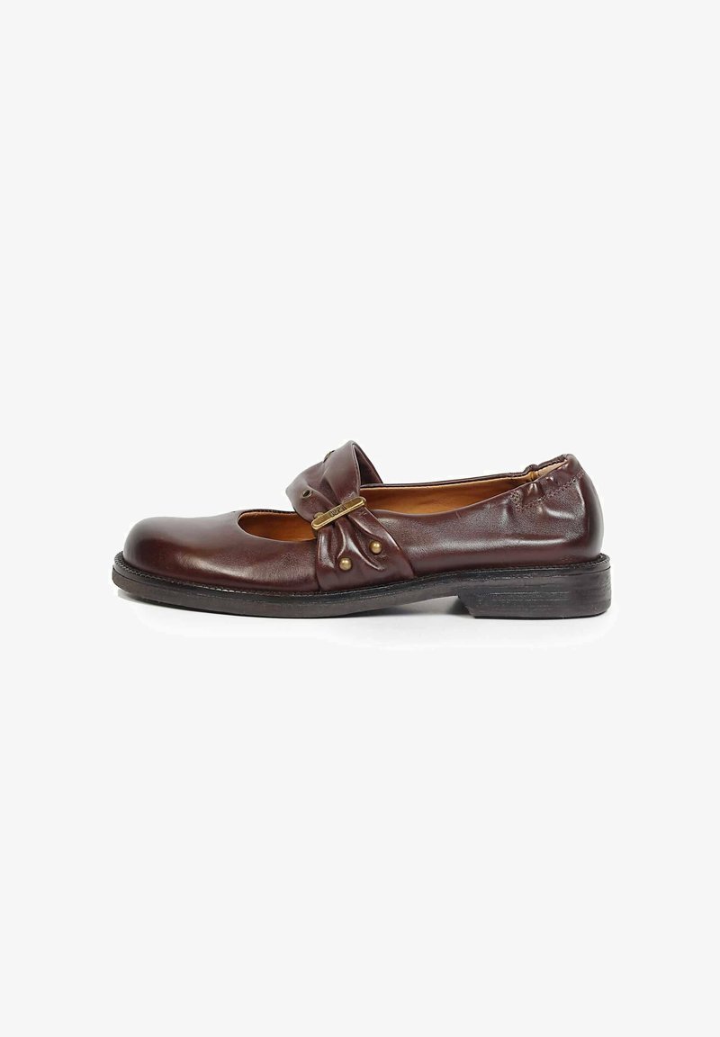 Chaussure Mary Jane en cuir marron foncé avec petit talon, bride latérale avec quincaillerie dorée et clous décoratifs, sur fond blanc.