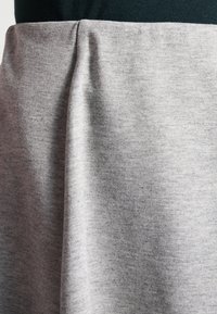 Jupe en coton grise avec une texture lisse et un motif chiné subtil, dotée d'une couture froncée à la taille.