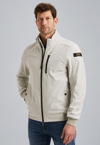 Light grey zip-up jacket with stand collar, side pockets, and a zippered chest pocket; features black hardware and a shoulder patch.