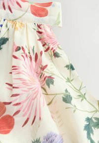 Abito floreale con sfondo crema, decorato con fiori rosa e rossi. Il tessuto è leggero, con pieghe raccolte e un colletto solido.