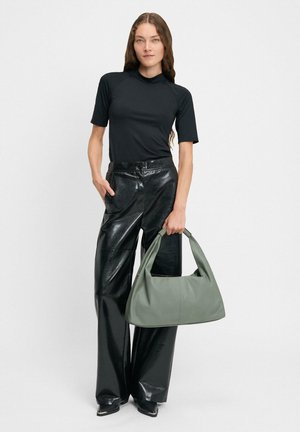 Czarna bluzka z krótkim rękawem, błyszczące skórzane spodnie z wysokim stanem oraz dużą zieloną skórzaną torbą z zakrzywionym uchwytem.