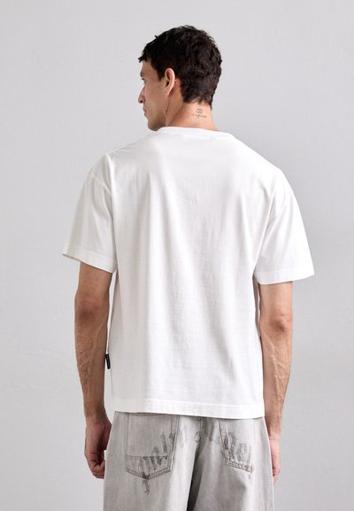 Hvit bomulls t-skjorte med korte ermer, avslappet passform og en noe rundet hem. Minimalistisk design uten synlige trykk eller mønstre.