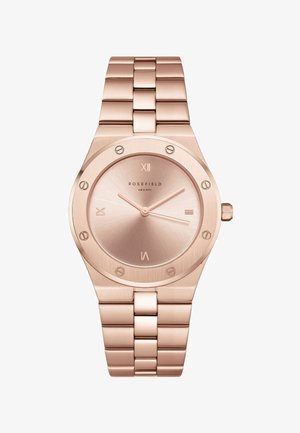 Montre-bracelet en métal or rose avec un bracelet à maillons, cadran rond, chiffres romains à 12, 3, 6, 9, et cadran minimaliste avec trois aiguilles.