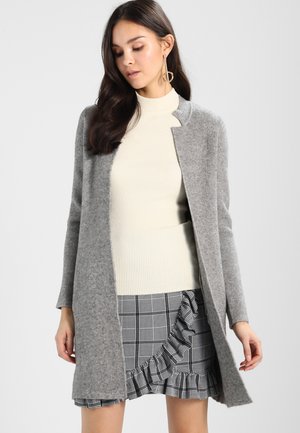Gray wool blend coat with open front design, long sleeves, and a smooth texture, paired with a ribbed cream sweater and a ruffled checkered skirt.