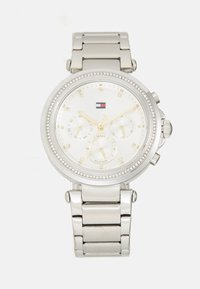Montre en acier inoxydable argenté avec un cadran rond blanc, des accents dorés, une lunette en cristal et des sous-cadrans chronographes multifacettes.