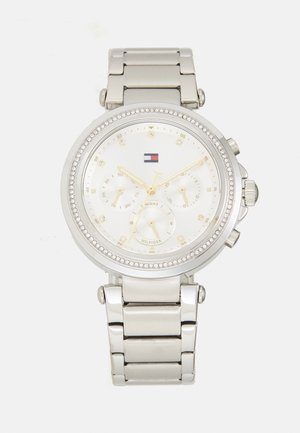 Montre en acier inoxydable argenté avec un cadran rond blanc, des accents dorés, une lunette en cristal et des sous-cadrans chronographes multifacettes.