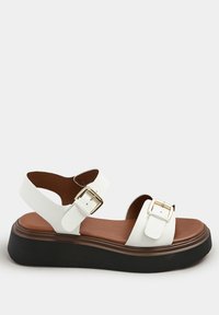 Sandalo bianco in pelle con due strap regolabili, fibbie dorate e una soletta marrone. Presenta una robusta suola piattaforma nera.