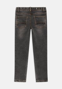 Gray denim jeans featuring a slim fit, five-pocket design, and contrasting orange stitching. Smooth texture with slight fading effect.