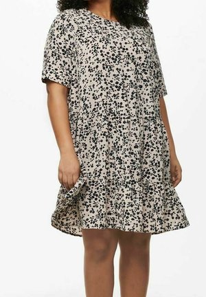 Vestido de manga corta en un tono beige claro con un diseño en capas, que presenta un patrón de lunares negros y un escote redondo. Tejido suave con un corte relajado.