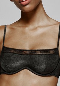 Zwart metalen bh met een gestructureerde vorm, voorzien van kantafwerking en verstelbare bandjes. Glad textuur met een subtiele glans.