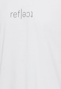 Hvid bomulds t-shirt med trykt tekst "ref|lec|t" i grå, placeret lodret i midten. Blød tekstur med klassisk pasform.
