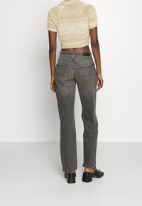 Jeans in denim grigio con gambe dritte, tasche posteriori e vita alta. Adatti ai fianchi, realizzati in un tessuto morbido e strutturato.