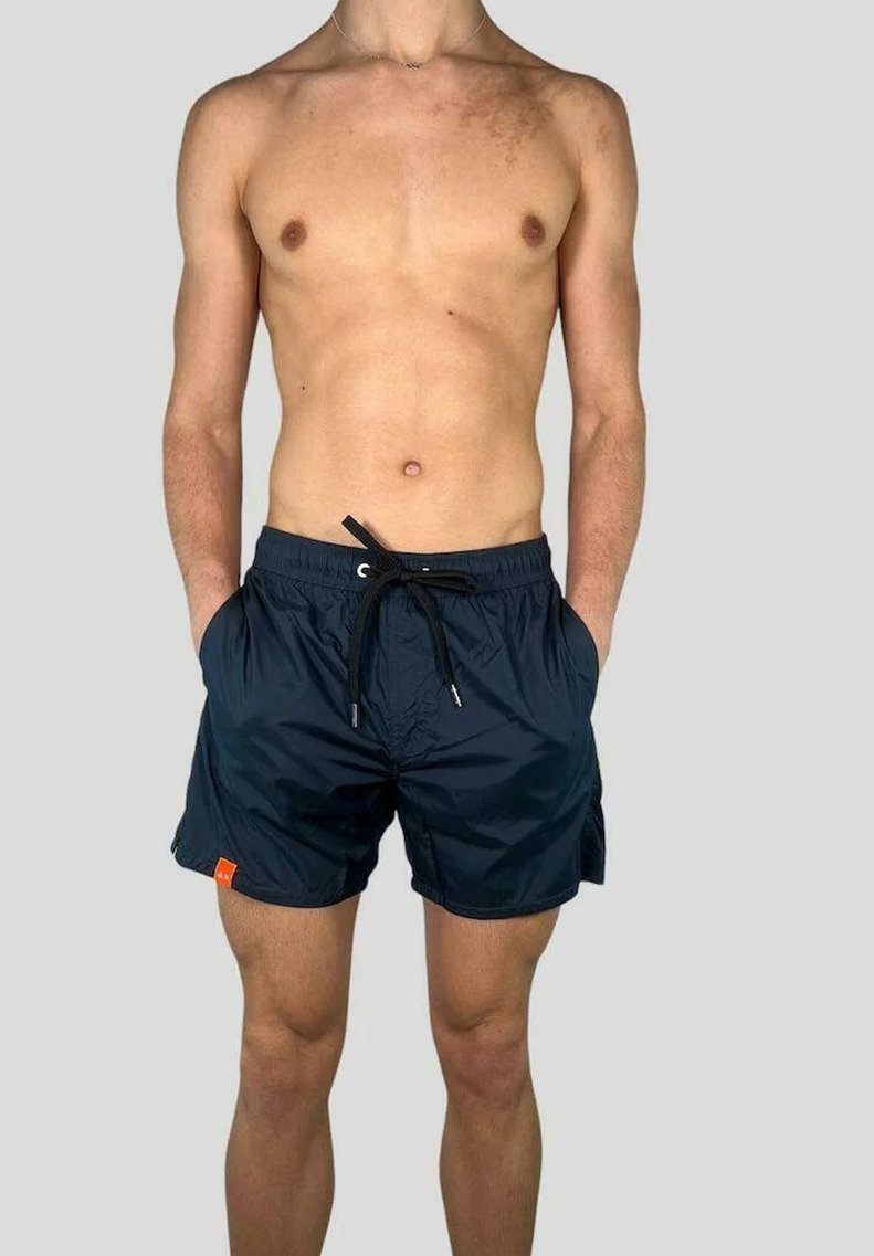 Pantaloni da bagno blu navy in tessuto leggero, dotati di una cintura elastica, tasche frontali e un piccolo logo arancione.