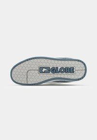 Semelle d'une basket présentant une semelle extérieure grise texturée avec des bords bleus et le mot « GLOBE » au centre.