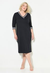 Černé šaty ke kolenům s výstřihem do V a rukávy tří čtvrtě. Obsahují bílé pruhované akcenty na okrajích rukávů, vyrobené z měkké tkaniny.