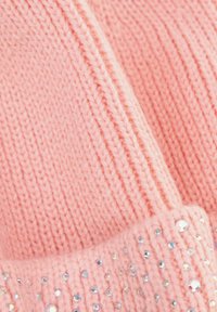 Różowa dzianinowa czapka z prążkowanym wzorem i błyszczącymi kryształkami na brzegu. Tekstura wydaje się miękka i przytulna.