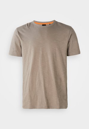 Sandfärgad t-shirt med kort ärm, tillverkad av mjukt tyg, med rund hals och en diskret logotyp i en mörkare nyans på vänster bröst.