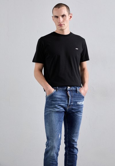 Black cotton t-shirt with a crew neck and small white logo, paired with blue denim jeans featuring a distressed finish and a button fly.