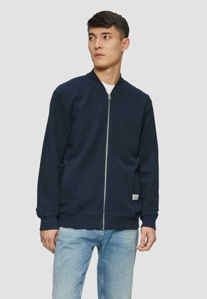 Navy zip-up sweatshirt with a round neckline, front pockets, and ribbed cuffs. Soft fabric, minimal design, suitable for casual wear.