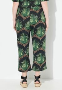 Zwarte cropped broeken met een groen palmbladerenpatroon en bruine accenten. Gemaakt van een lichtgewicht materiaal, met een platte tailleband en wijde pijpen.