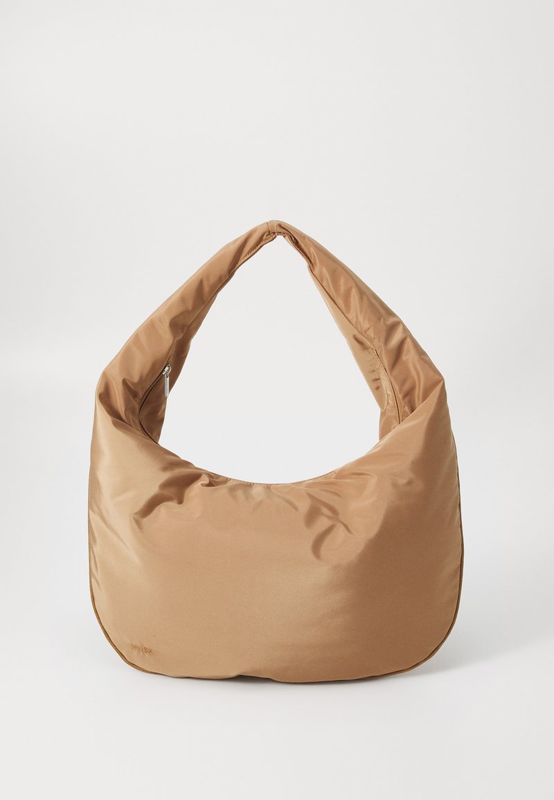 Sac hobo en nylon marron avec une texture lisse et douce, une large sangle courbée et une fermeture à glissière en haut. Branding minimal sur le côté.