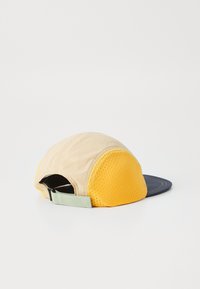 Beige szövetből készült sapka sárga hálós betéttel, navy csúccsal és a hátsó oldalon állítható világoszöld pánttal.