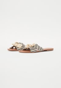 Sandaler med striper i beige og svart, med en knyttet overdel, flat såle i brune nyanser og en teksturert finish.