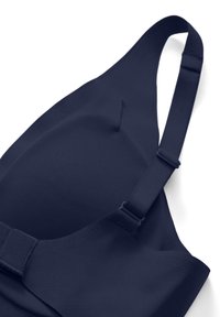 Reggiseno modellato senza cuciture blu navy con spalline regolabili e fascia inferiore larga, mostrato disteso su sfondo bianco.