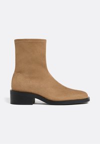 Stivaletto in suede marrone con gambale alto, punta arrotondata e tacco a blocco nero. Presenta un dettaglio di cucitura minima lungo il bordo superiore.