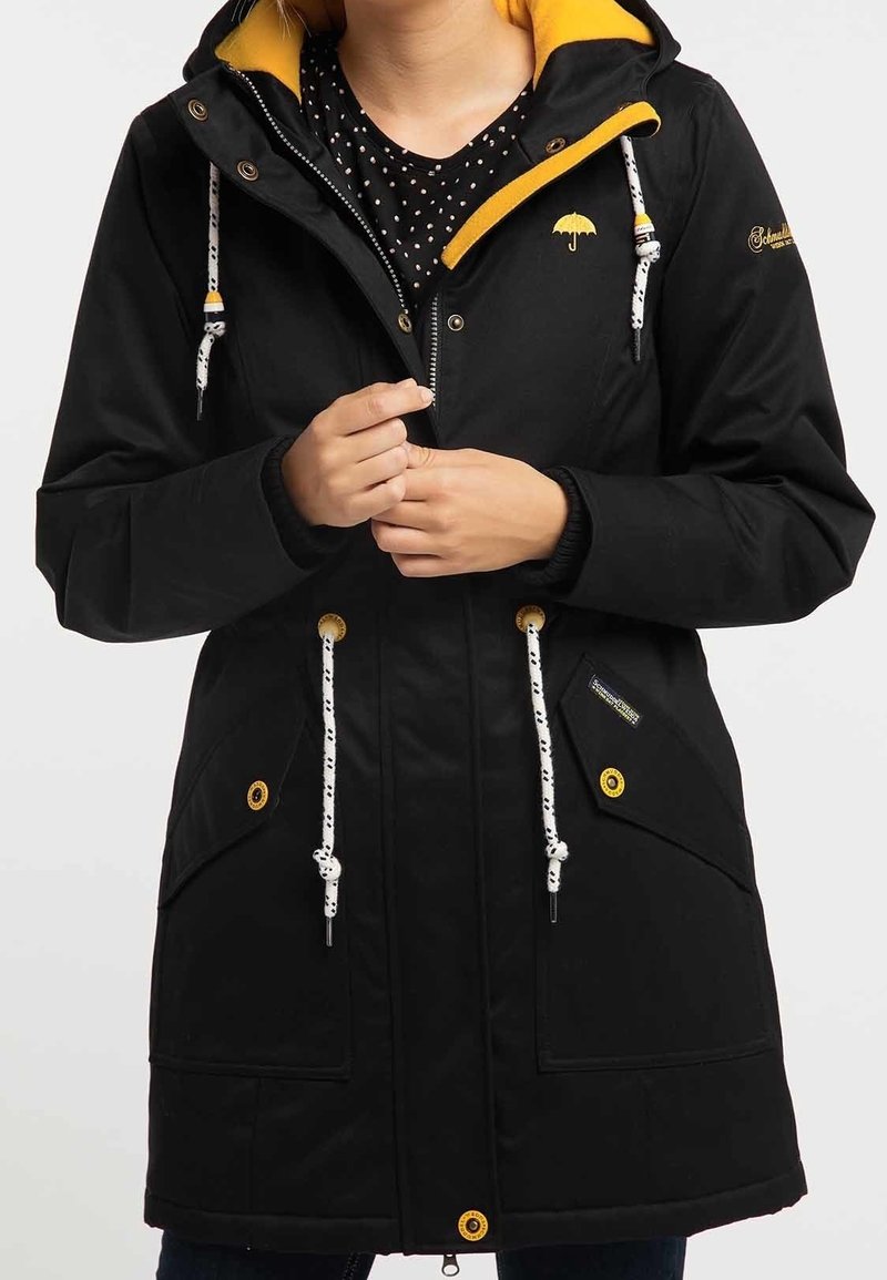 Svart vattentät parka med gul fodrad huva, justerbara dragskor, två framfickor och logotypdetalj. Hållbart tyg med texturerad yta.