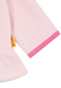 Helles rosa Fleece-Oberteil mit einem gerafften Saum, ausgestattet mit einem kontrastierenden rosa Bündchen und einem gelben Etikett mit einem Logo.