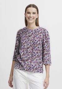 Floral blouse featuring a mix of purple, blue, and beige hues, bateau neckline, three-quarter sleeves, and a slightly loose fit.