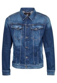 Jeansjacka i medelblått med två bröstfickor, knappstängning och en lätt blekning. Har sömdekoration på ärmarna.