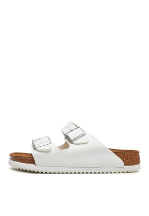 White sandals featuring two adjustable buckles, cork footbed, textured rubber outsole, and a minimalist design with a smooth finish.