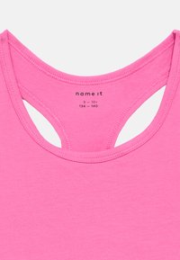 Ροζ αμάνικη μπλούζα με στρογγυλή λαιμόκοψη και ανοίγματα στην πλάτη. Κατασκευασμένη από μαλακό ύφασμα με ελάχιστες ραφές, με ετικέτα μέγεθος 9-10 ετών.