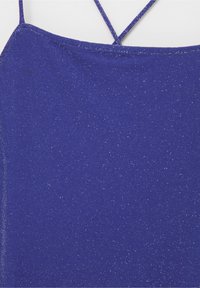 Ärmlös topp i djupt blått tyg med en subtil shimmer. Har tunna korsade axelband och en slät, texturerad yta.