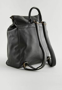 Sac à dos en cuir noir avec deux bretelles ajustables, une poignée supérieure, une surface texturée et une fermeture éclair en haut. Détails en métal doré.