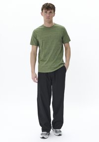 Tricou verde din heather cu mânecă scurtă, asortat cu pantaloni negri lejeri și pantofi sport gri. Design simplu, textură moale, ajustare relaxată.
