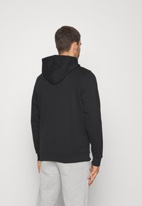 Sudadera negra con capucha ajustable, puños y cinturilla de canalé. La tela parece suave con un diseño de color sólido.