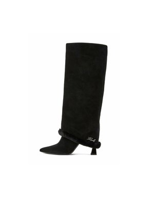 Botte haute noire en daim avec bout pointu, petit talon incliné et bordure en fourrure près de la cheville brodée d'une signature.