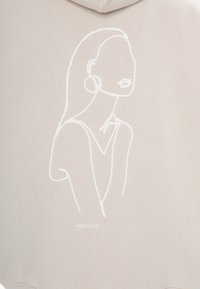 Crème sweatshirt met een witte geborduurde abstracte gezichtontwerp, met een gladde textuur en een subtiele, minimalistische esthetiek.