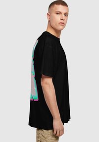 Sort oversized t-shirt med farverig grafikdesign på bagsiden. Kortærmet og løs pasform, lavet af blødt bomuldsstof.