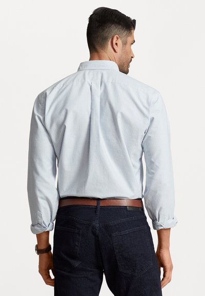 Lyseblå stribet skjorte med lange ærmer og bred krave, parret med mørke jeans og et brunt bælte. Struktureret stof.