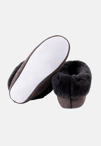 Mørkebrune slippers med blødt sort pelsfoer og en ydre af ruskind. Har en hvid gummisål og en syet sømdetalje.