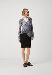 Langermet, gjennomsiktig bluse med et blått og grått abstrakt mønster, lagdelt over en hvit topp; kombinert med et svart blyantskjørt og flate sandaler.