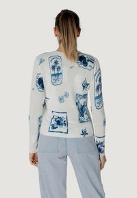 Maglione bianco con stampe grafiche blu, inclusi fiori e etichette in stile vintage. Maniche lunghe con polsini e orlo a coste. Vestibilità casual.