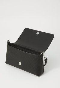 Svart clutch-veske med teksturert mønster, sølvfarget tilbehør og magnetisk lukking. Har ett rom og en justerbar stropp.